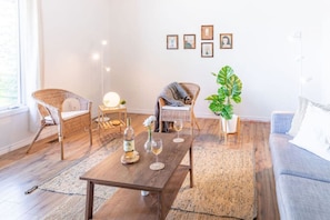 A living room with wicker furniture, a wooden coffee table, and a large plant. - Fun, Relaxing Cottage w Hot Tub, Sauna & Fast Wifi (Buckhorn)