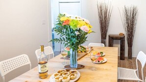 Une table à manger avec une bouteille de vin, des assiettes remplies de nourriture et un vase de fleurs.