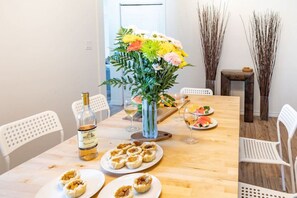 A dining table with a bottle of wine, plates of food, and a vase of flowers. - Fun, Relaxing Cottage w Hot Tub, Sauna & Fast Wifi (Buckhorn)