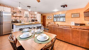 Een moderne keuken met een houten kookeiland, roestvrijstalen apparatuur en een eethoek met een houten tafel gedekt voor vier personen.