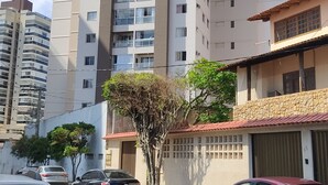 A multi-story residential building with balconies, a gated entrance, and parked cars. - Vista da Orla de Itapoã - 1002 (Itapuã Vila Velha)