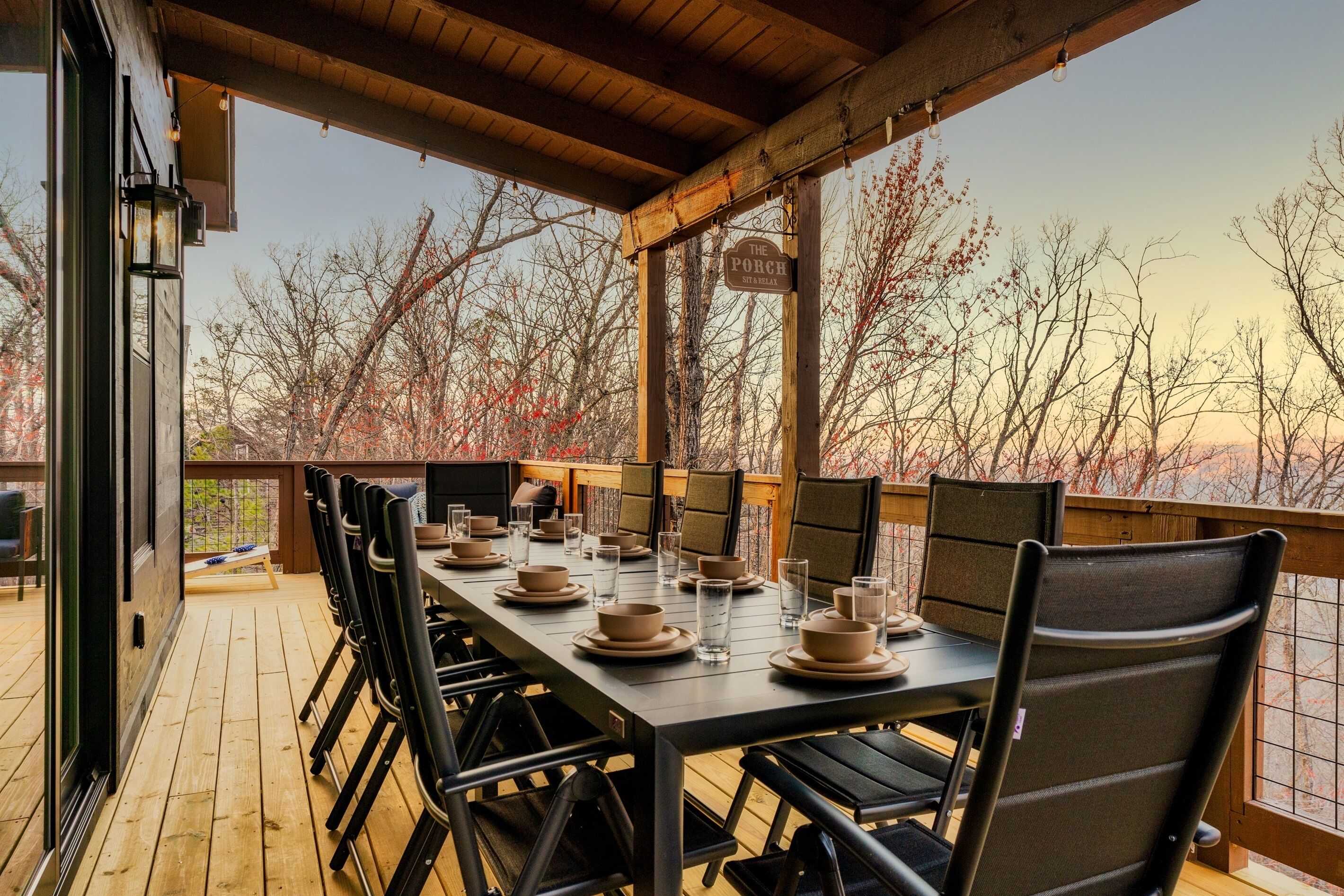 A covered outdoor dining area with a long table set for four, surrounded by chairs, and a sign indicating 'The Porch'.