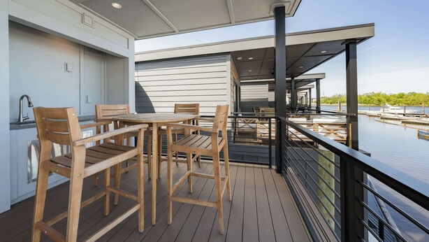 Eine Terrasse mit Holzmöbeln und Blick auf einen Yachthafen.