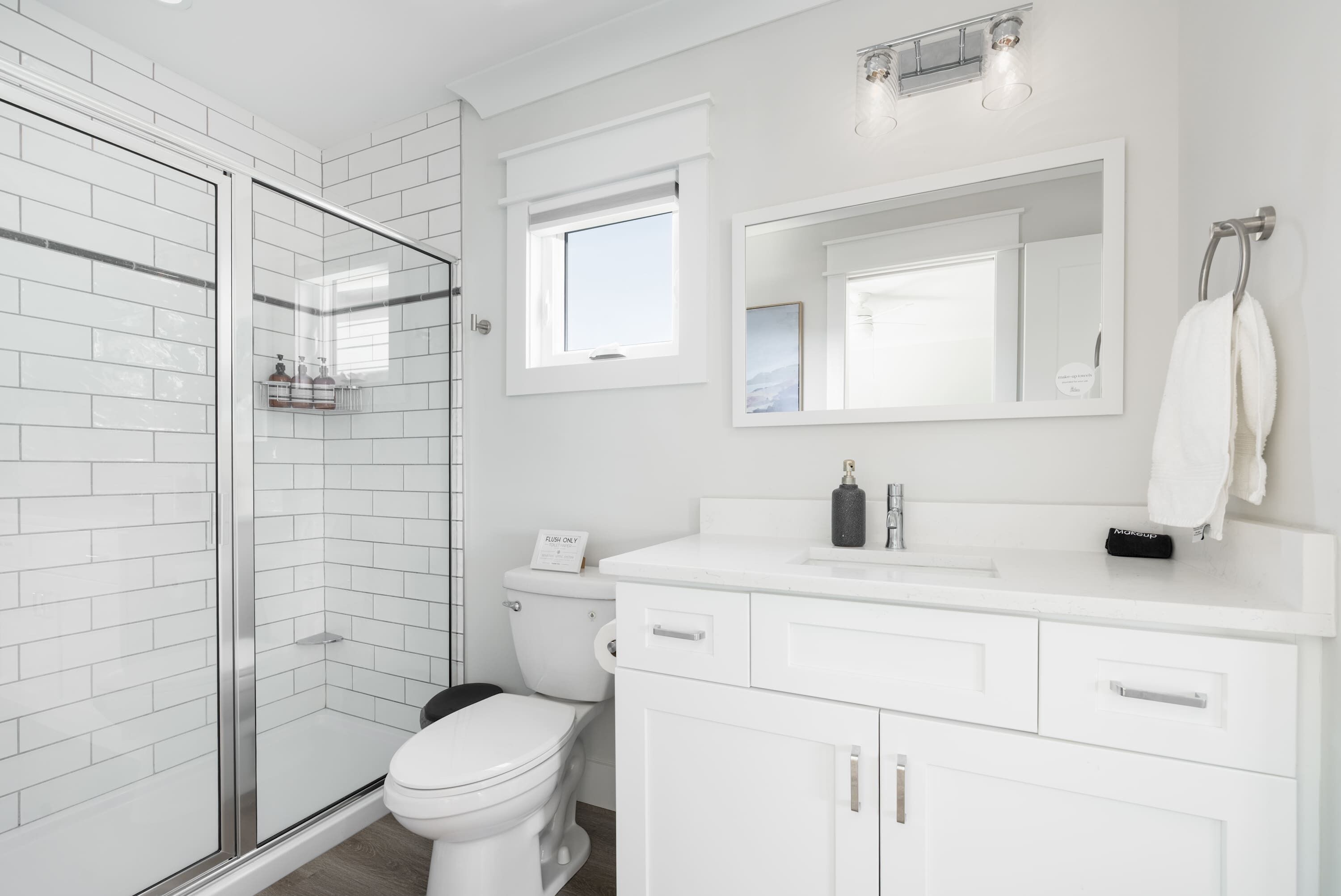 Un baño moderno con cabina de ducha de vidrio, inodoro y tocador con espejo.
