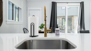 Eine moderne Küche mit Spüle aus Edelstahl, einem Wasserhahn aus Bambus und einer Handseifenflasche.