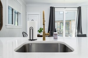 A modern kitchen with a stainless steel sink, a bamboo water tap, and a bottle of hand soap.