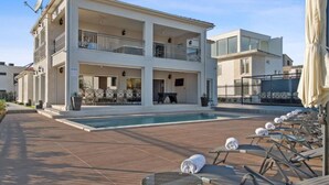 A two-story building with a swimming pool, outdoor seating, and a covered area with umbrellas. - Villa Carolus in Vodice - Five Bedroom Villa with Terrace and Swimming pool (Vodice)