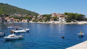 A coastal town with boats docked along the waterfront, a sandy beach, and buildings with red-tiled roofs.