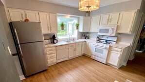 Una cocina moderna con armarios blancos, electrodomésticos de acero inoxidable y suelo de madera.