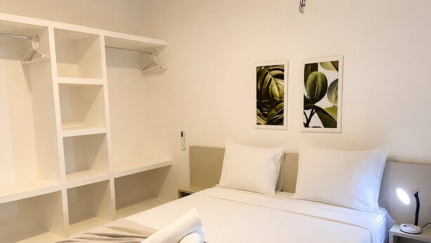Habitación de hotel con cama, armario, dos cuadros en la pared y una lámpara de noche.