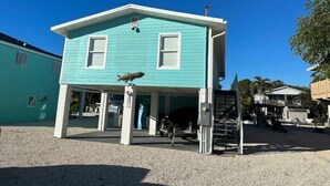 A turquoise two-story house with a covered porch and a small staircase leading to the entrance. - Endless Summer Beach House
 (Cudjoe Key)