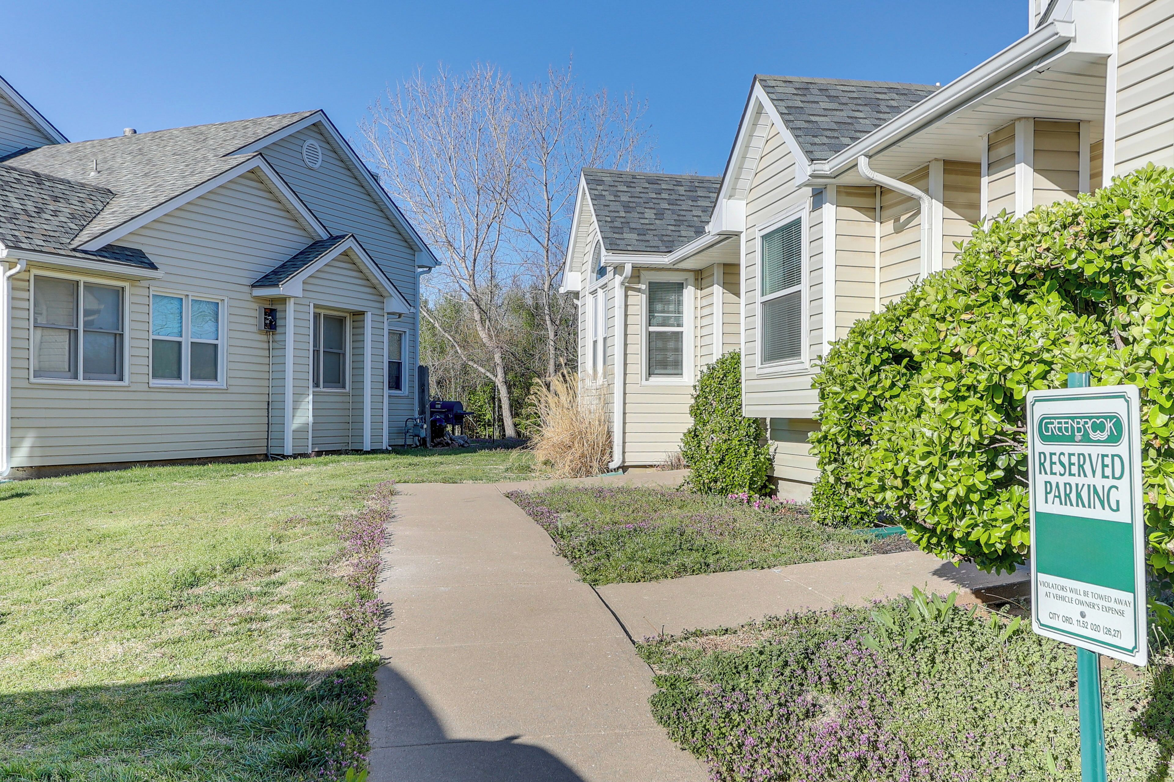 A residential area with a 'Greenbush Reserved Parking' sign, houses with sloped roofs, and a well-maintained lawn.