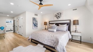 Un dormitorio con una cama, lámparas de noche, ventilador de techo y alfombra.