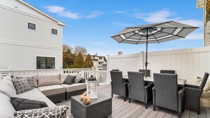 Una terraza con un sofá, sillas, una mesa y una sombrilla.