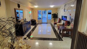 A hotel lobby with a reception desk, seating area, and a large mirror.