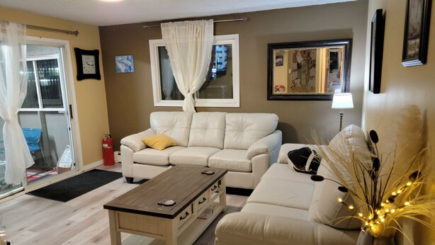 A living room with a beige sofa, a wooden coffee table, and a vase with dried plants.