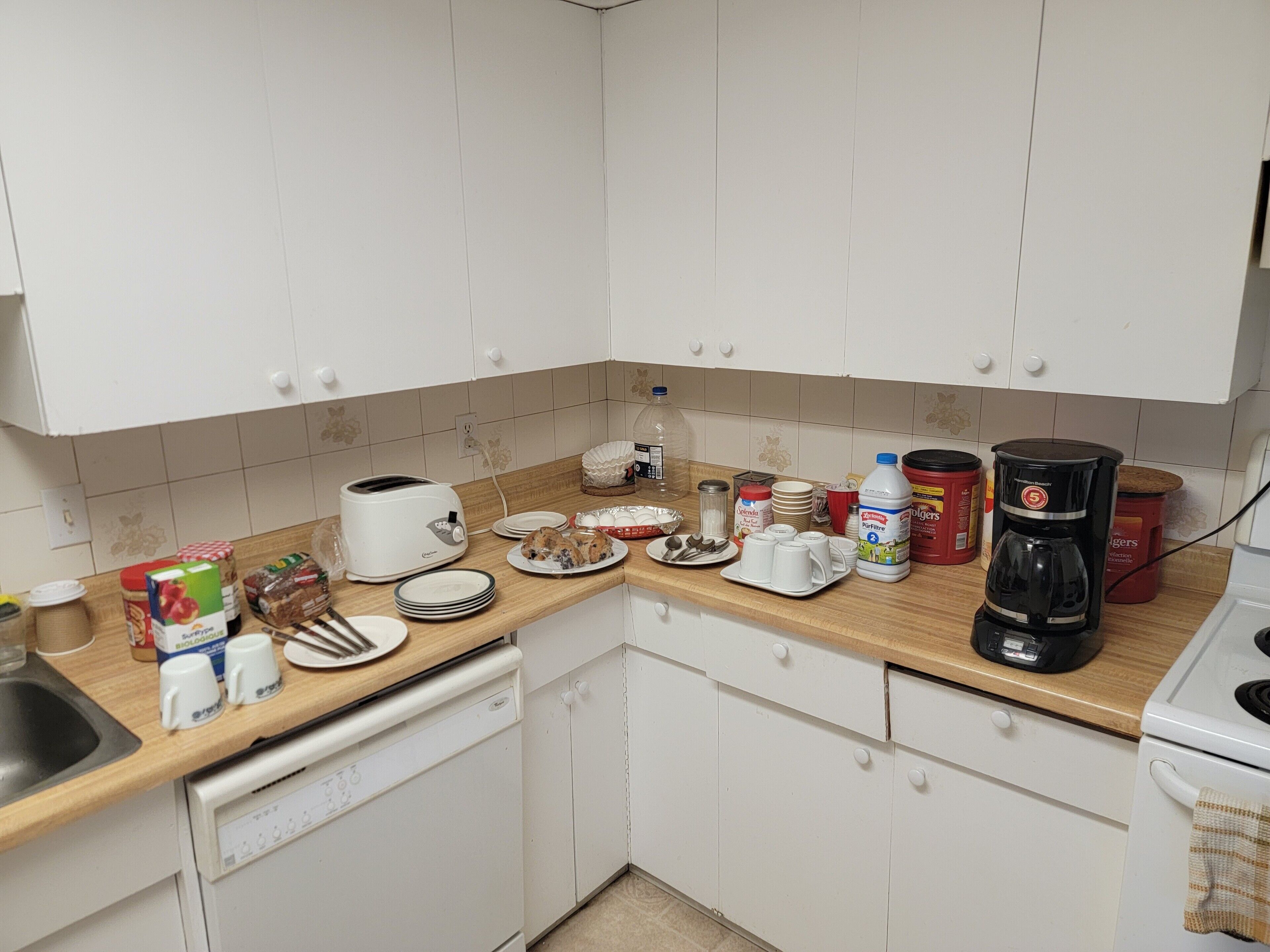 A kitchen with white cabinets, a wooden countertop, a toaster, a coffee maker, and various kitchen items.