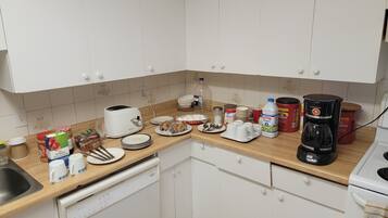 A kitchen with white cabinets, a wooden countertop, a toaster, a coffee maker, and various kitchen items.