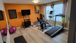 A home gym with exercise equipment, a treadmill, and a yoga mat.