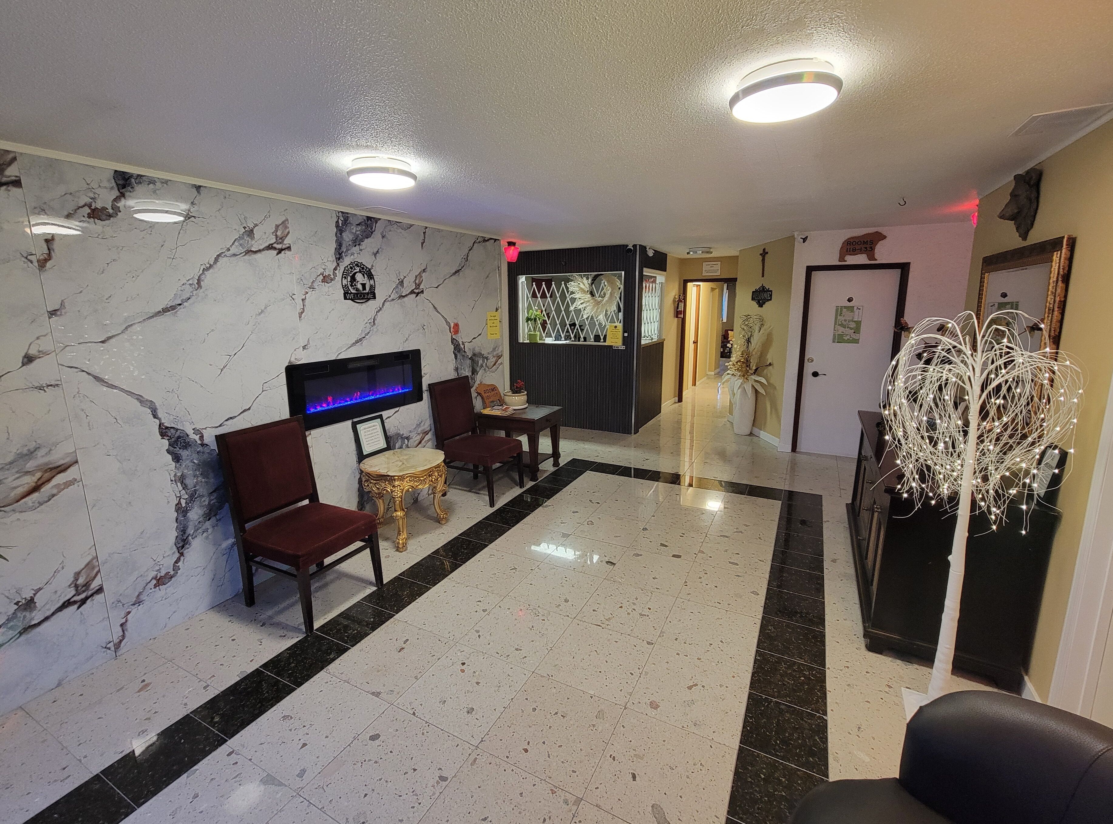A lobby with marble walls, a reception desk, seating area, and a decorative tree.
