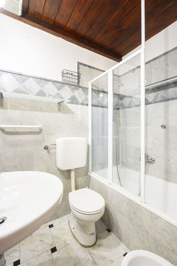 A bathroom with a white toilet, a white sink, and a glass-enclosed shower.