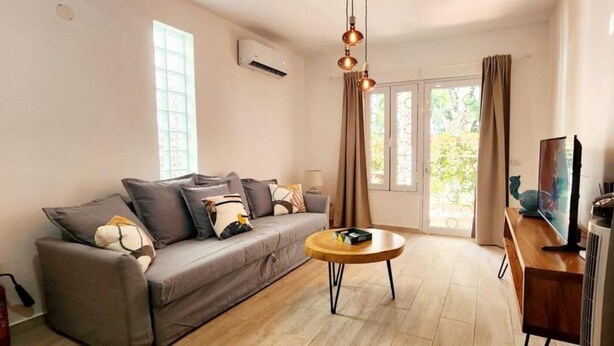 A living room with a sofa, a coffee table, a TV, and a heater. - Apartamento Bayahibe Con Terraza (San Rafael del Yuma)