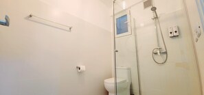 A modern bathroom with a glass shower enclosure, a toilet, and a towel rack. - Apartamento Bayahibe Con Terraza (San Rafael del Yuma)