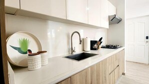 A modern kitchen with a sink, stove, and cabinets. - Apartamento Bayahibe Con Terraza (San Rafael del Yuma)