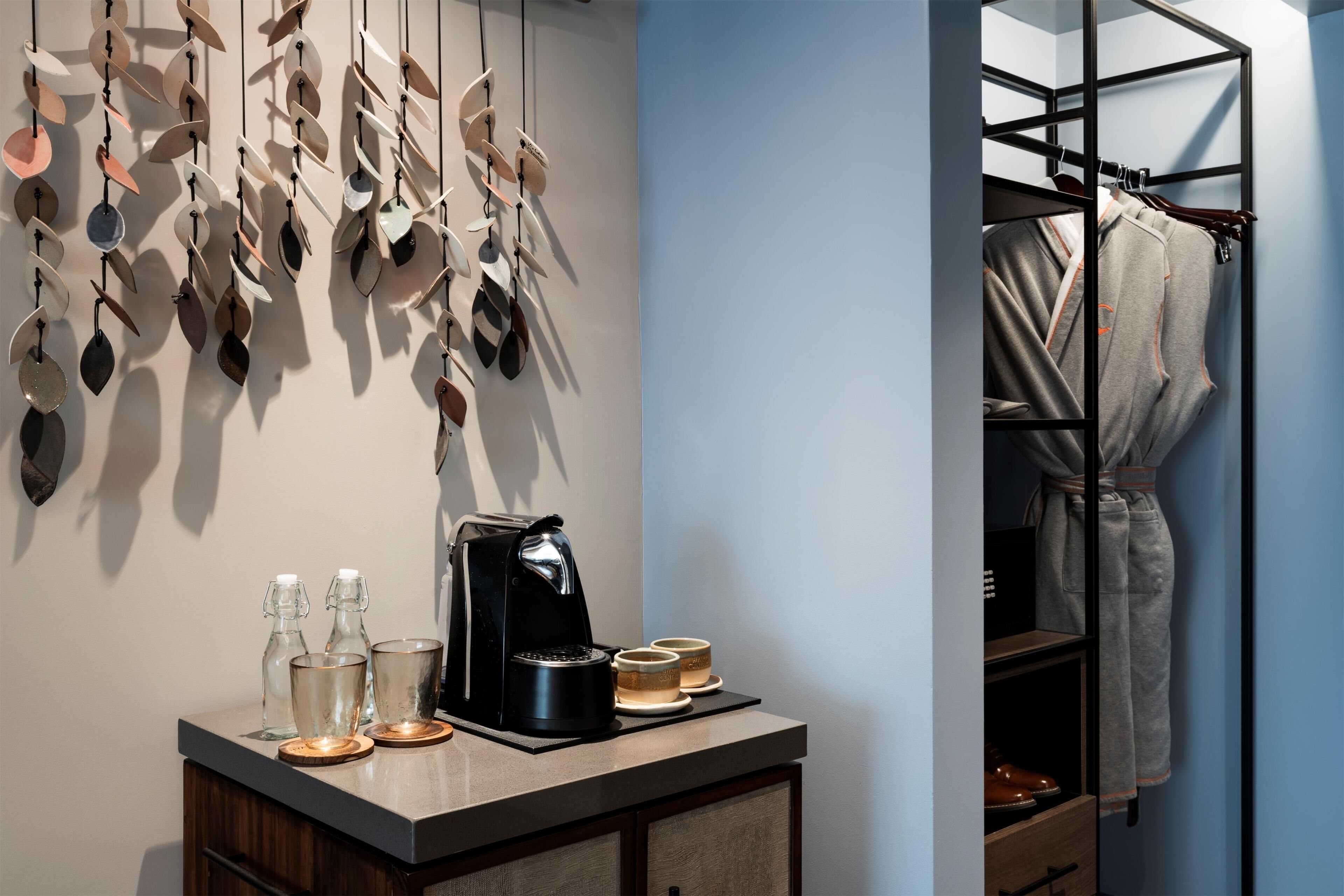 A modern bathroom with a coffee machine, glasses, and a towel rack.