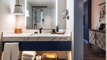 Un baño moderno con tocador de mármol, un espejo grande y zona de ducha.