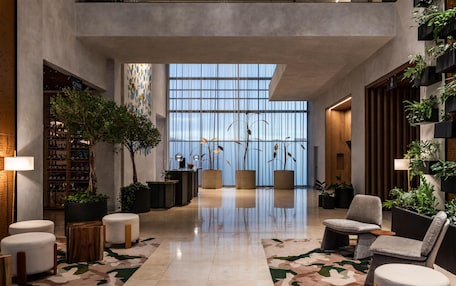 A spacious lobby with a high ceiling, large windows, and a variety of seating options.