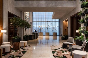 Eine großzügige Lobby mit hoher Decke, großen Fenstern und verschiedenen Sitzmöglichkeiten.