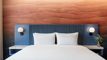A modern hotel room with a large bed, two bedside tables, and a textured wall.