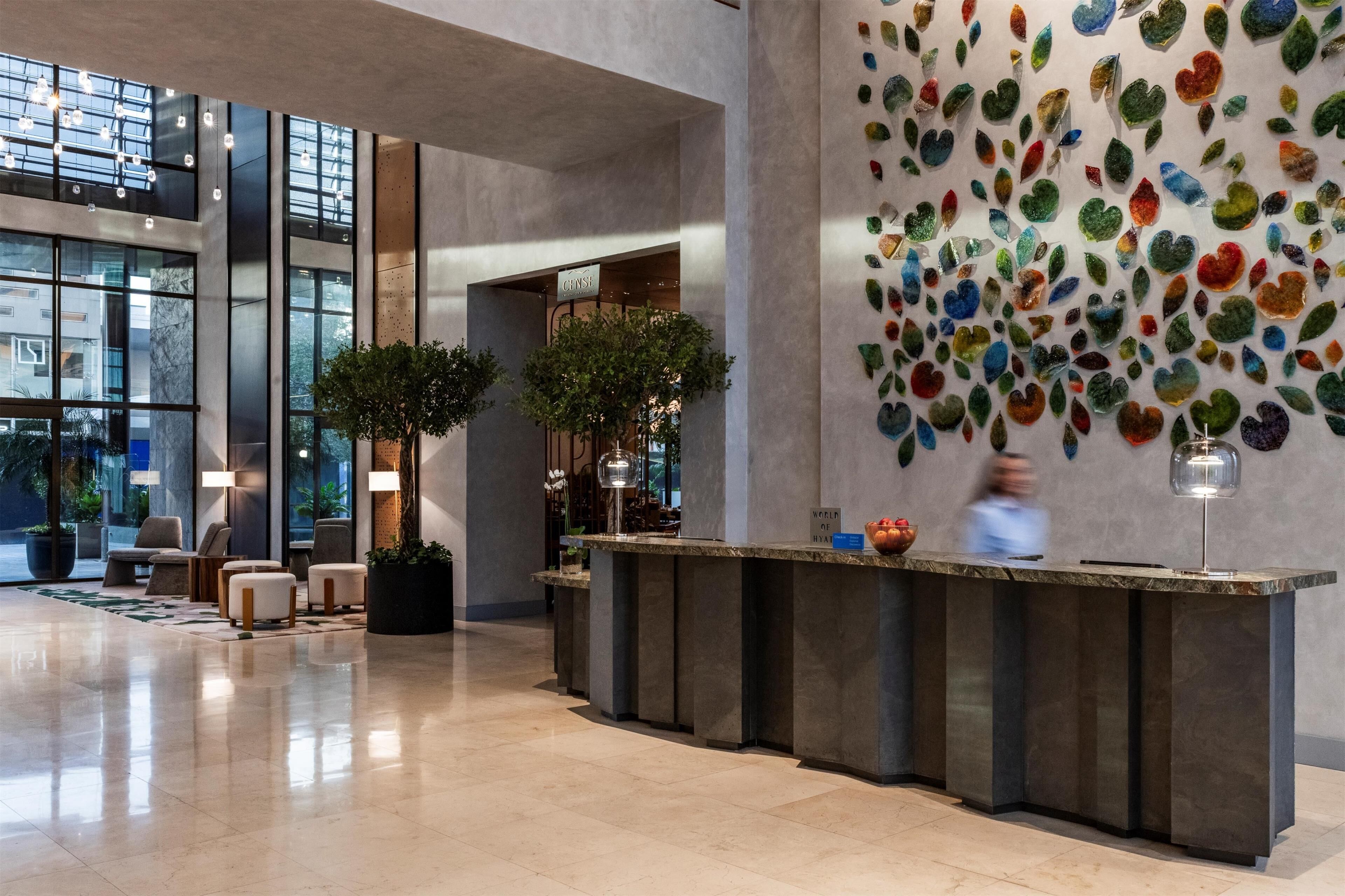 A modern lobby with a reception desk, seating area, and large windows.