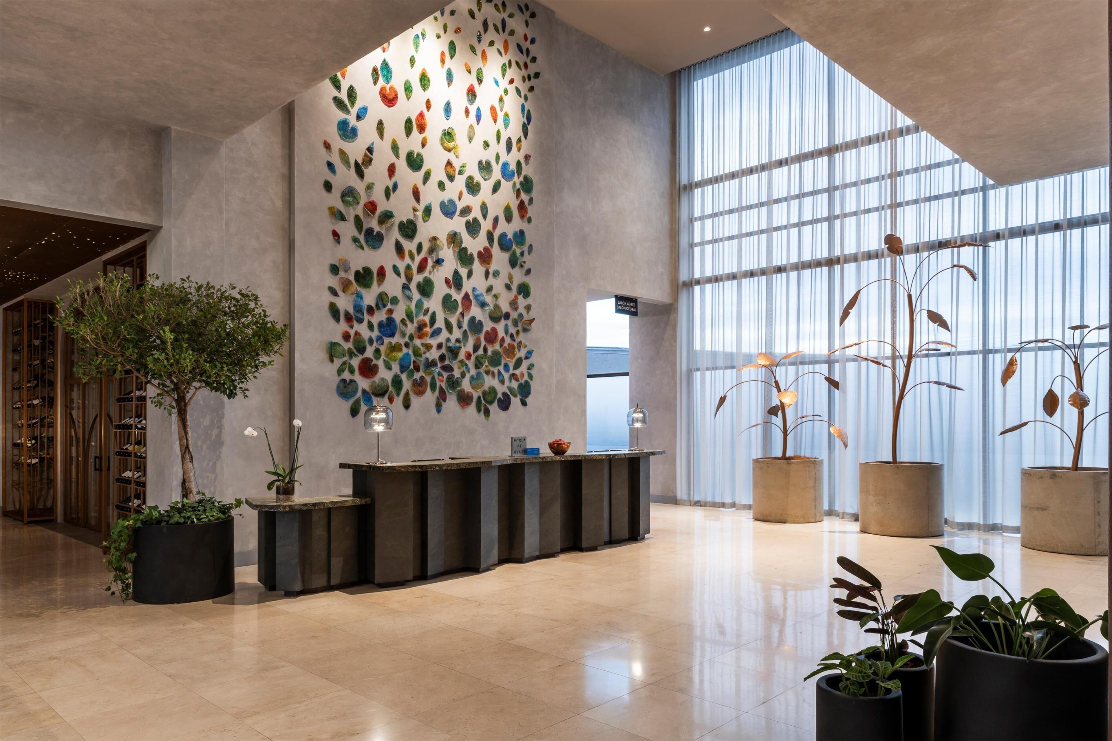 A modern lobby with a reception desk, large windows, and a decorative wall.