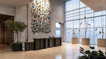 A modern lobby with a reception desk, large windows, and a decorative wall.