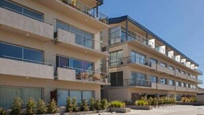 Un hotel de varios pisos con balcones, ventanas amplias y un patio empedrado.