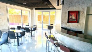 Un comedor moderno con mesas, sillas, una barra y un ventanal con vista a una valla de madera.
