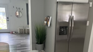 Une cuisine moderne avec un réfrigérateur en acier inoxydable, une plante en pot et une chaise rose.