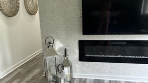 Un salon moderne doté d’un grand téléviseur à écran plat fixé au mur, d’une décoration murale et d’un plancher en bois.