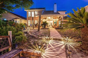 A two-story house with a paved driveway, outdoor seating area, and a well-maintained garden. - Waterfront-Pets/Kayaks*LT Discounts (Panama City)