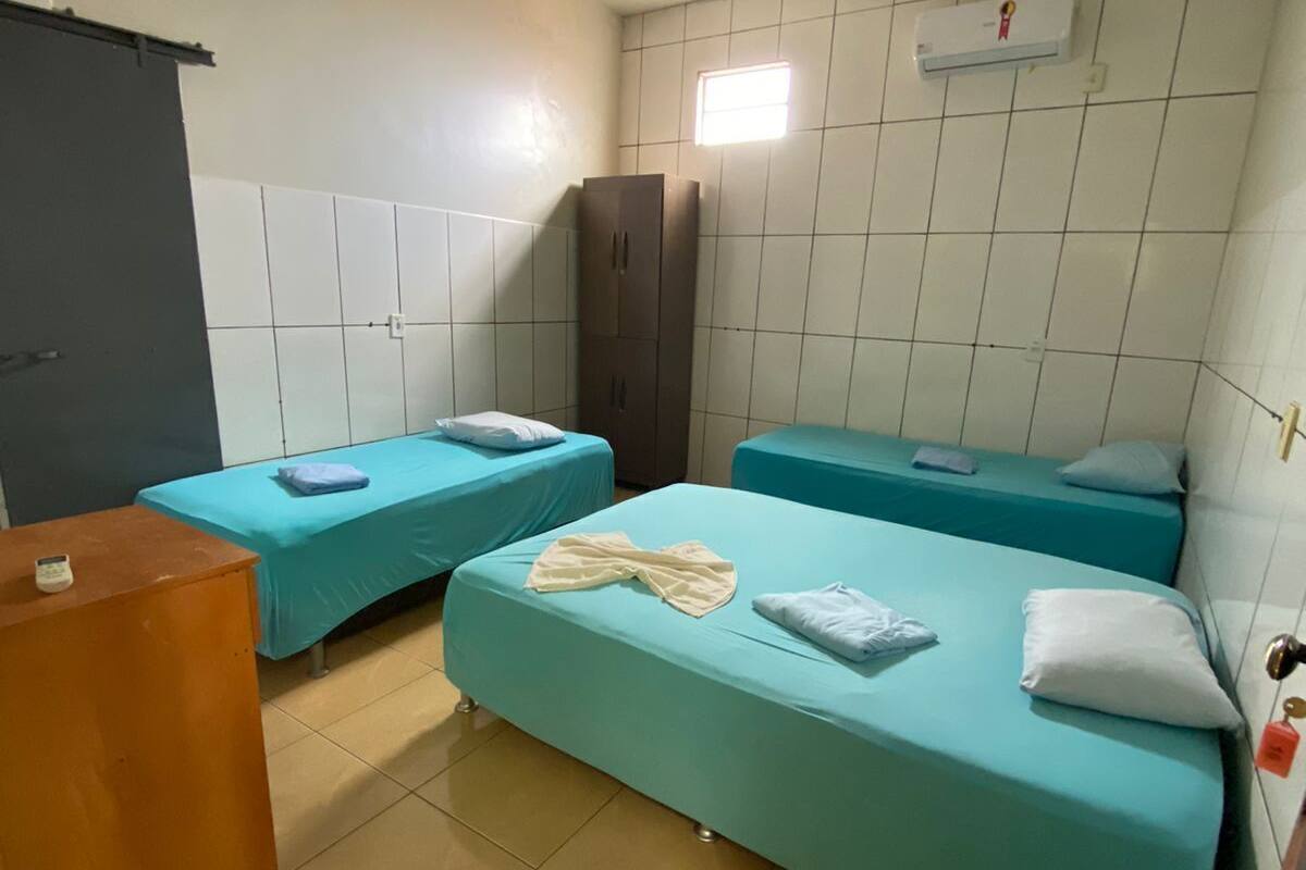 A room with two single beds, a wardrobe, a desk, and a tiled floor.