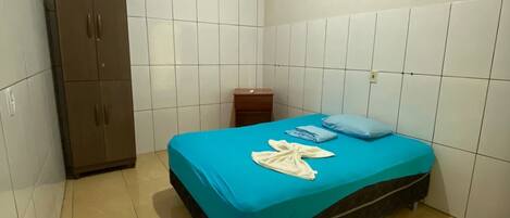 Una habitación pequeña y limpia con una cama, un armario y un equipo de aire acondicionado en la pared.