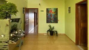 A hallway with a skylight, a painting of parrots, and a water fountain. - Hotel ferraz (Tucumã)
