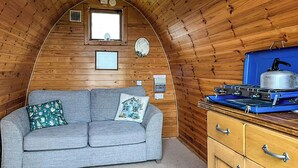 A cozy cabin interior with a sofa, a kettle, and wooden walls.