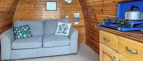 L’intérieur d’un chalet chaleureux, avec un canapé, une bouilloire et des murs en bois.