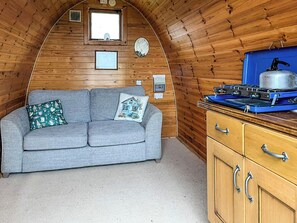 Ein gemütliches Blockhaus-Interieur mit einer Couch, einem Wasserkocher und Holzwänden.