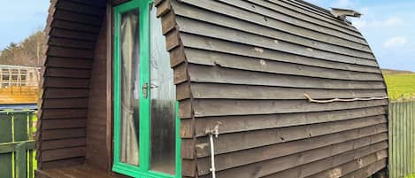 Une cabane en bois avec une porte verte, un petit porche et un toit en pente.