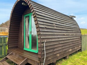 Eine Holzhütte mit grüner Tür, einer kleinen Veranda und einem geneigten Dach.