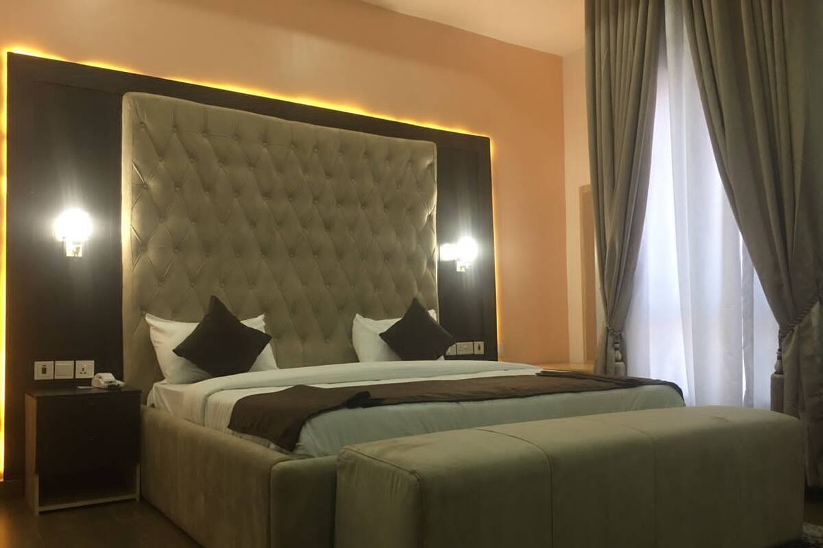 Ein Schlafzimmer mit einer gepolsterten Kopfteile, einem Bett mit Kissen, einem Nachttisch und einem Beistelltisch.